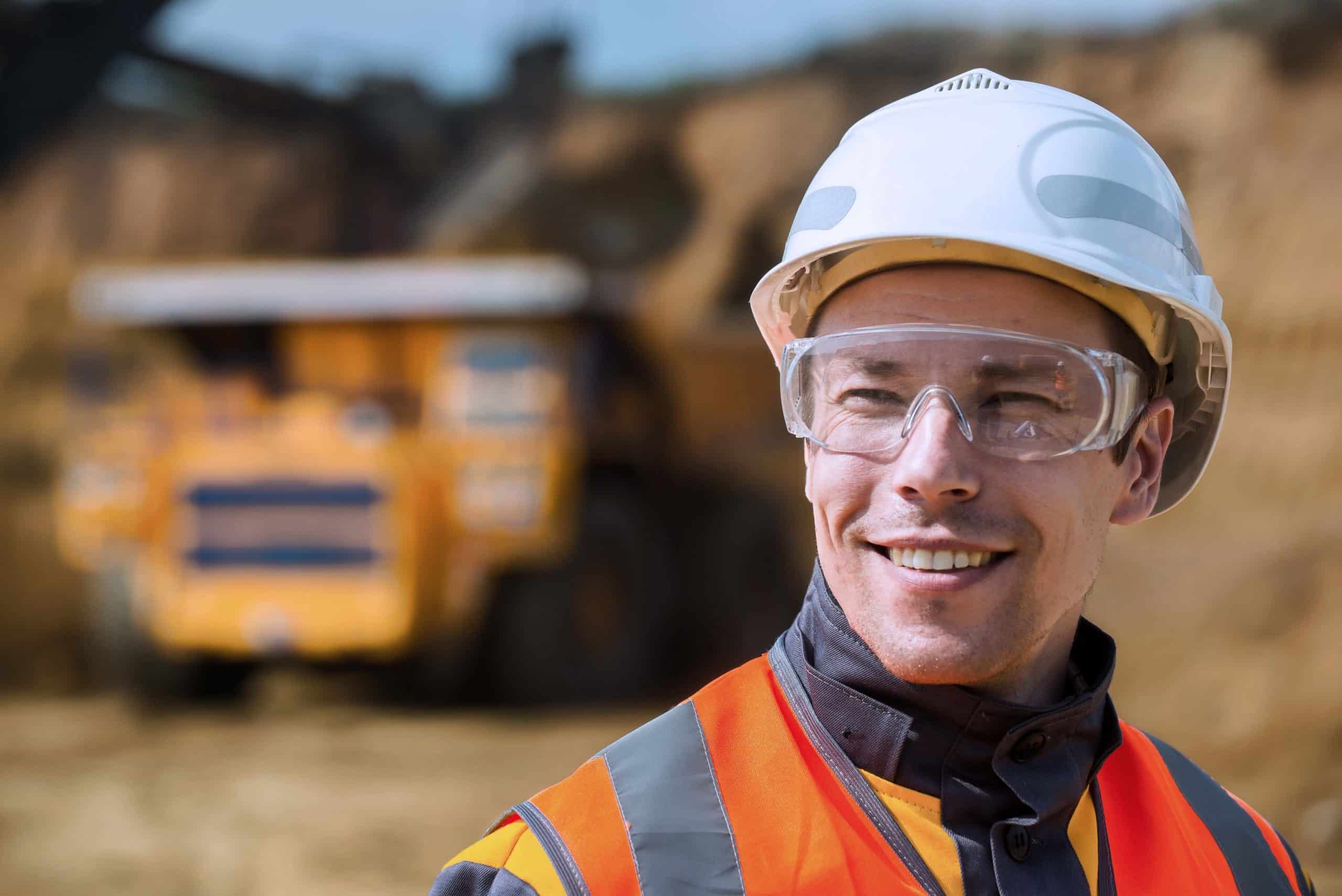 Mine worker with huge truck on the background in open pit